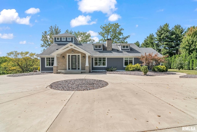 view of front of house featuring roof with shingles and curved driveway