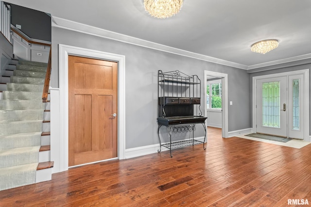 entryway featuring ornamental molding, stairs, a notable chandelier, and wood finished floors