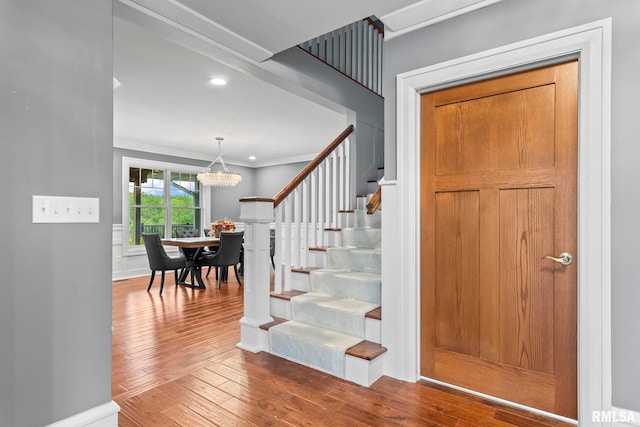 interior space featuring crown molding, a chandelier, baseboards, and hardwood / wood-style flooring