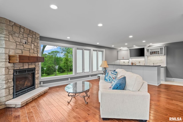 living area with a fireplace, wood finished floors, and recessed lighting