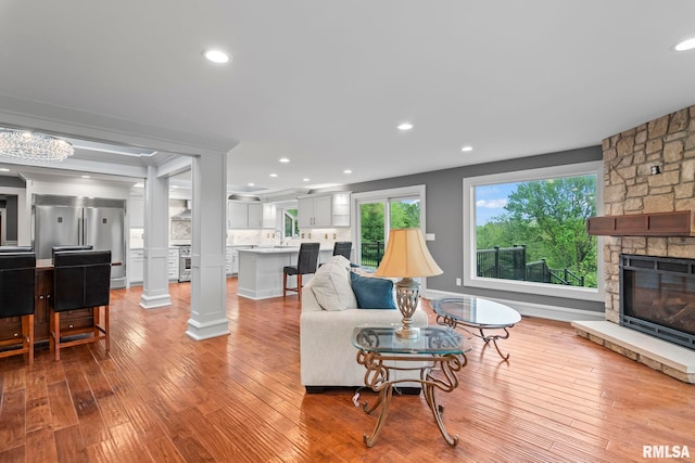 living room featuring light wood-style flooring, a stone fireplace, and recessed lighting