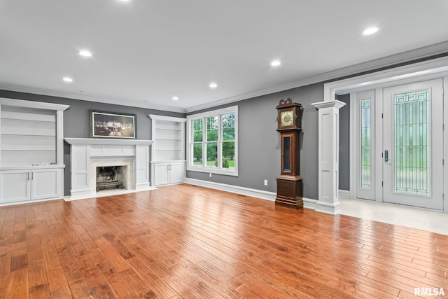 unfurnished living room featuring light wood finished floors, crown molding, a fireplace, and recessed lighting