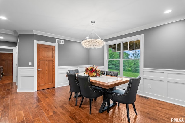 dining area with a wainscoted wall, visible vents, a decorative wall, a chandelier, and ornamental molding