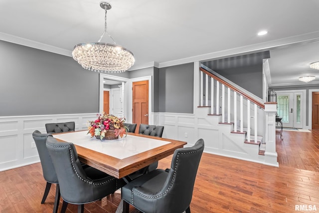 dining room featuring an inviting chandelier, stairway, a decorative wall, and ornamental molding