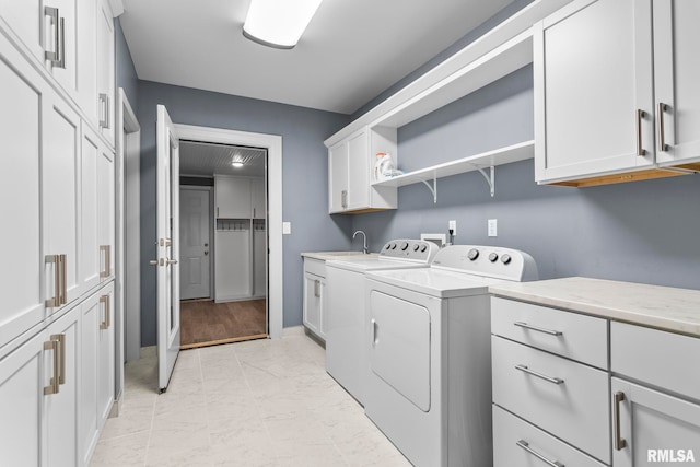 washroom featuring a sink, cabinet space, marble finish floor, washing machine and clothes dryer, and baseboards
