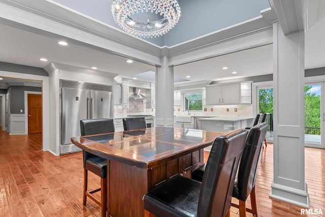 dining room featuring an inviting chandelier, a wealth of natural light, light wood-style flooring, and crown molding