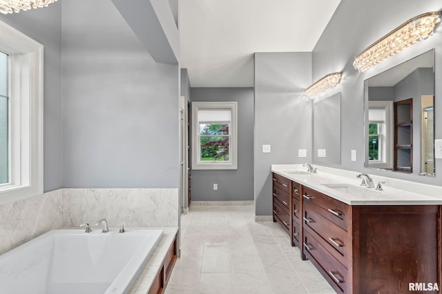 bathroom with marble finish floor, double vanity, a sink, and a tub