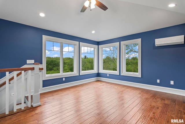 empty room with a ceiling fan, baseboards, a wall mounted air conditioner, and wood-type flooring