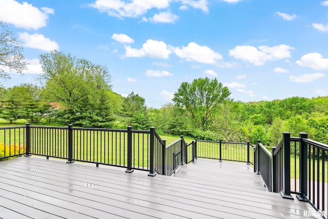 wooden terrace featuring a wooded view and a yard