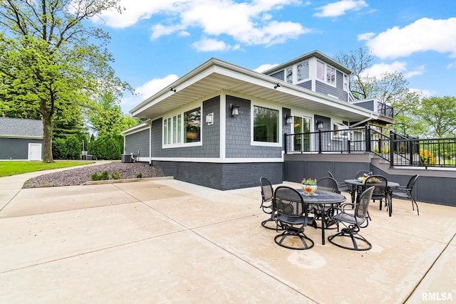 exterior space featuring cooling unit, outdoor dining area, a patio area, and brick siding