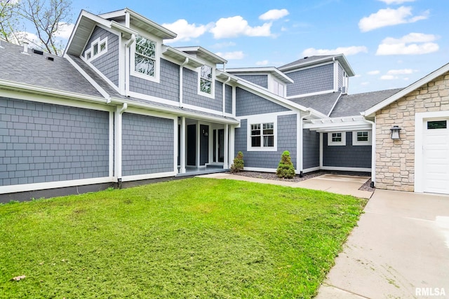 view of front of property with roof with shingles and a front lawn