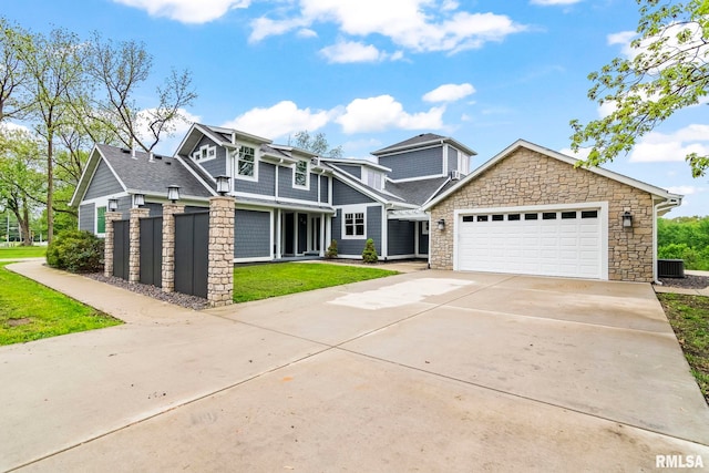 craftsman-style home with concrete driveway, stone siding, a front lawn, and an attached garage