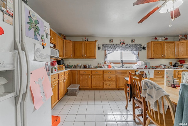 kitchen with a sink, white appliances, light countertops, and light tile patterned floors