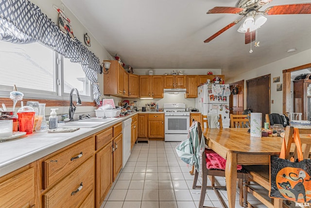 kitchen with light tile patterned floors, a sink, white appliances, under cabinet range hood, and light countertops