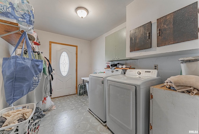 clothes washing area with light floors, cabinet space, and washer and clothes dryer