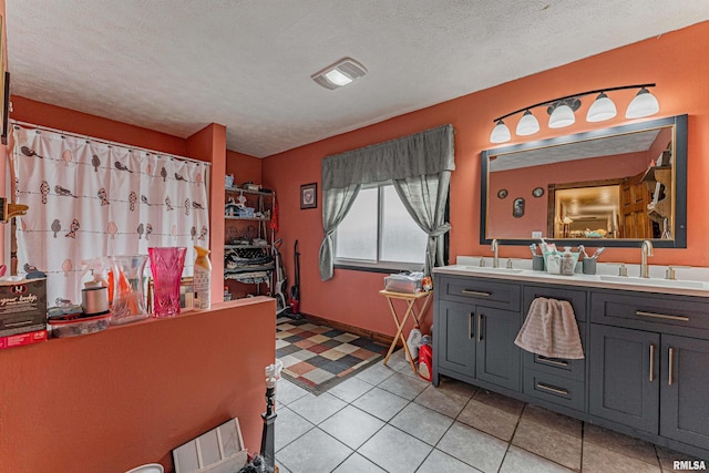 full bath featuring a sink, a textured ceiling, tile patterned flooring, double vanity, and baseboards