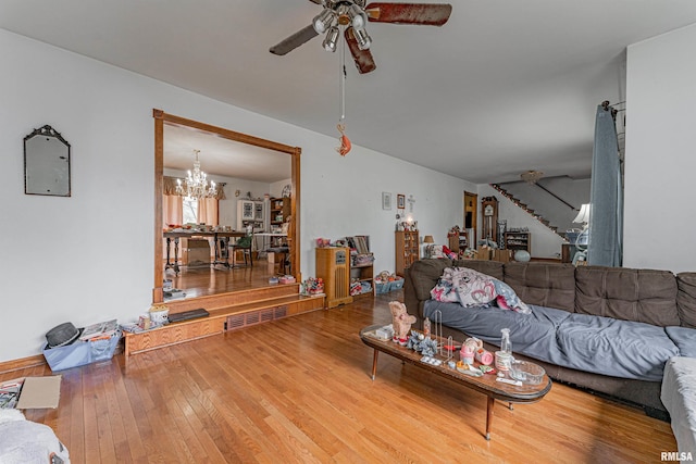 living room featuring stairway, ceiling fan with notable chandelier, and hardwood / wood-style floors