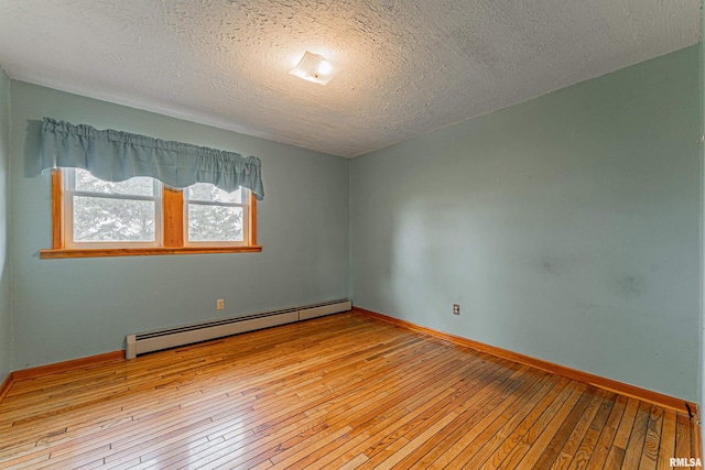 spare room with a baseboard heating unit, baseboards, light wood-type flooring, and a textured ceiling