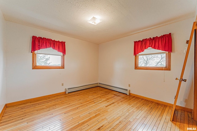 unfurnished room featuring a textured ceiling, baseboards, light wood-style flooring, and a baseboard radiator