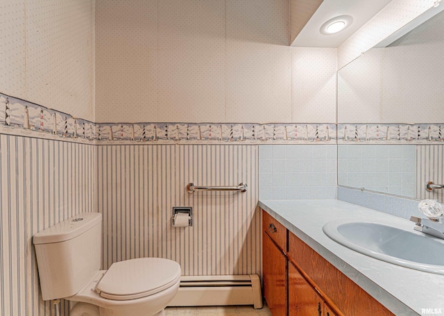 bathroom featuring a baseboard radiator, toilet, wallpapered walls, and vanity