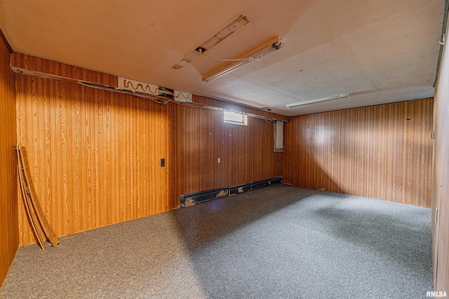 empty room featuring a baseboard radiator, wood walls, and carpet floors