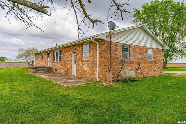 back of house featuring a patio area, brick siding, and a lawn
