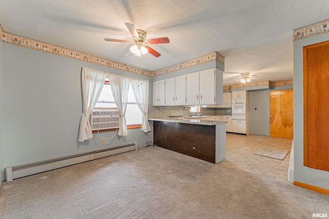 kitchen featuring a ceiling fan, a baseboard radiator, a textured ceiling, white oven, and a peninsula