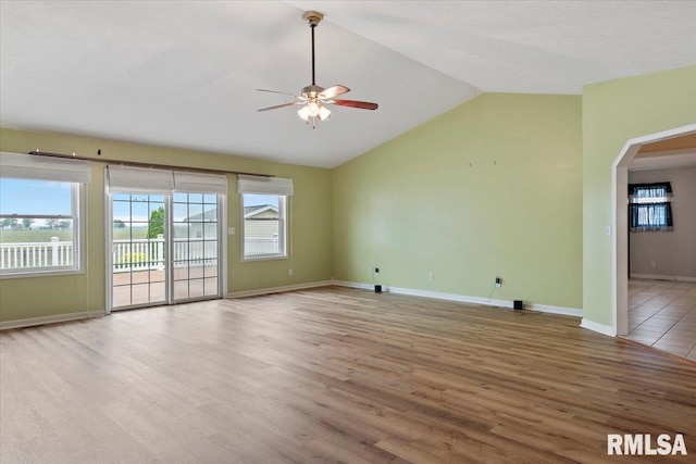 unfurnished living room featuring wood finished floors, a ceiling fan, a wealth of natural light, arched walkways, and vaulted ceiling