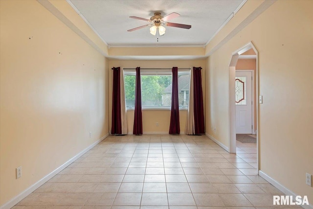 empty room with crown molding, arched walkways, ceiling fan, and light tile patterned floors