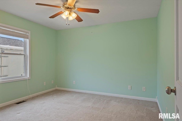 empty room featuring light colored carpet, visible vents, baseboards, and ceiling fan