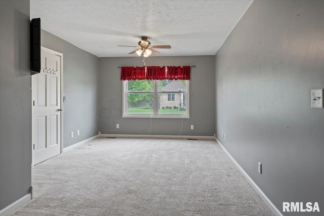 empty room featuring carpet, a textured ceiling, baseboards, and ceiling fan