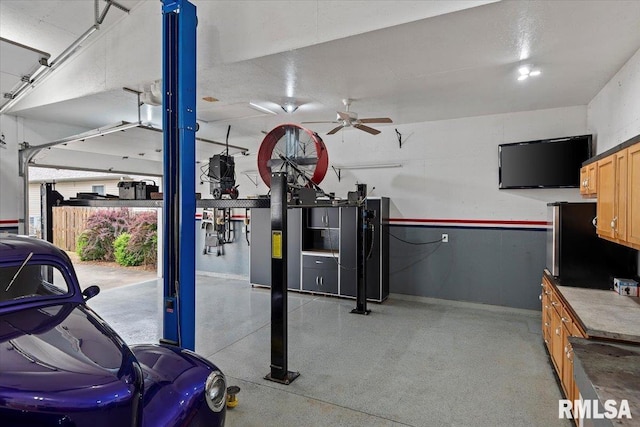 garage with freestanding refrigerator, baseboards, and ceiling fan