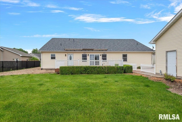 rear view of house with fence and a lawn