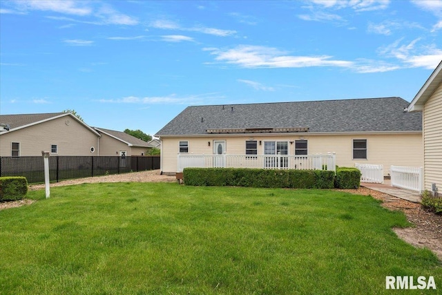 rear view of property featuring a lawn and fence