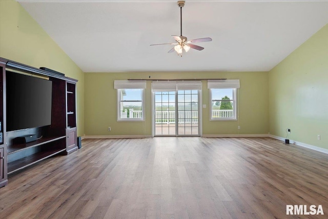 unfurnished living room with lofted ceiling, a healthy amount of sunlight, ceiling fan, and wood finished floors