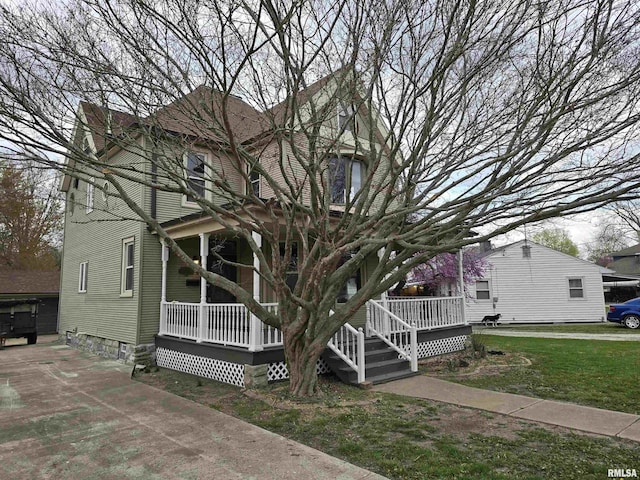 victorian-style house featuring covered porch and a front lawn
