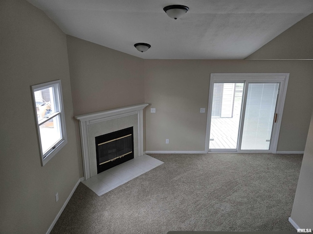 unfurnished living room featuring carpet, a tiled fireplace, and lofted ceiling