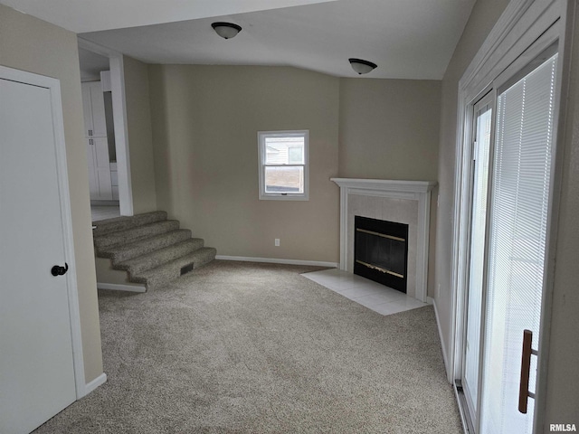 unfurnished living room featuring carpet, baseboards, a premium fireplace, and stairs