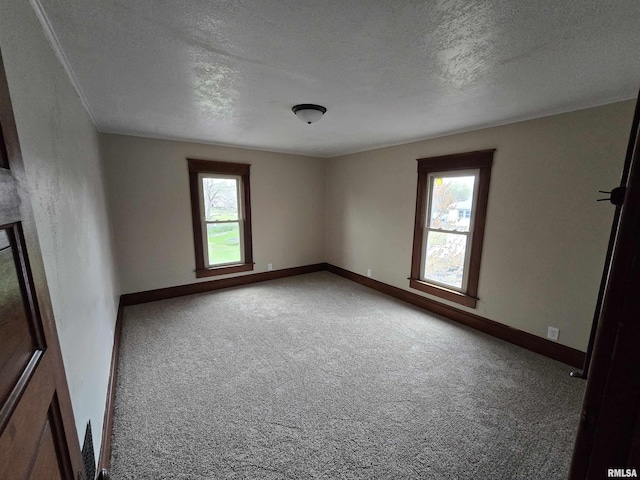 carpeted spare room with a textured ceiling and baseboards