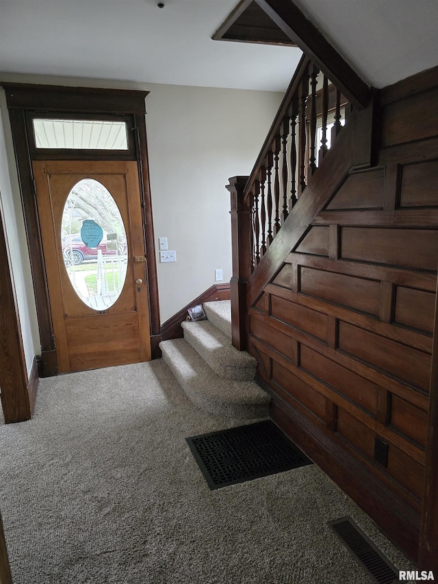 carpeted entrance foyer with visible vents, baseboards, and stairs