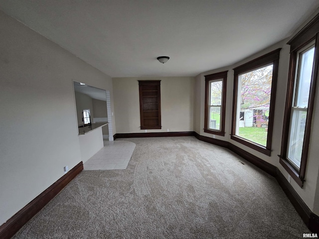 unfurnished living room with baseboards and light carpet