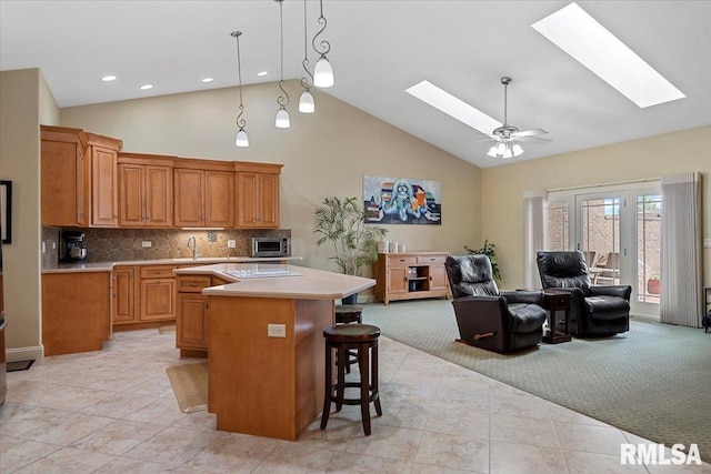 kitchen featuring light countertops, a kitchen island, a skylight, and high vaulted ceiling