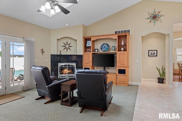 living area with light colored carpet, visible vents, vaulted ceiling, ceiling fan, and a premium fireplace