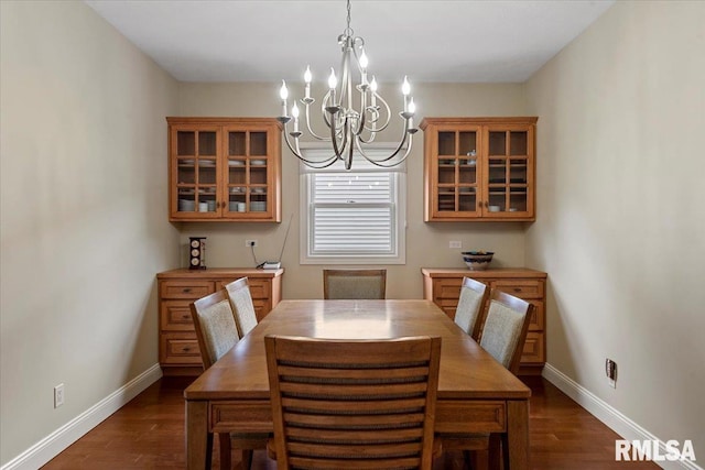 dining space with dark wood finished floors, baseboards, and a notable chandelier