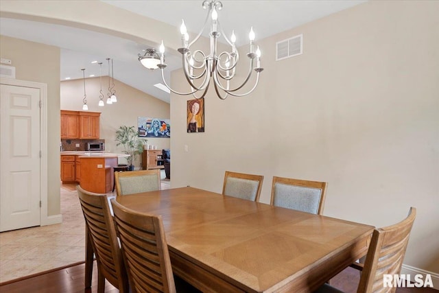 dining area with light wood finished floors, an inviting chandelier, visible vents, and vaulted ceiling