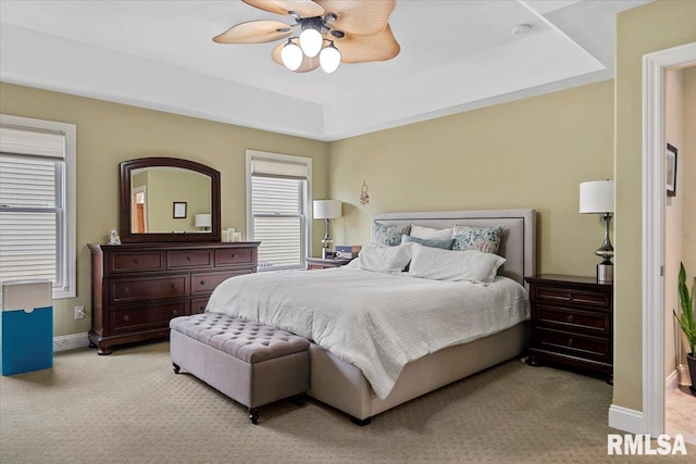 bedroom featuring a tray ceiling, baseboards, ceiling fan, and carpet floors