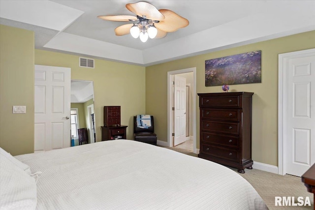 carpeted bedroom featuring baseboards, a raised ceiling, ceiling fan, and visible vents