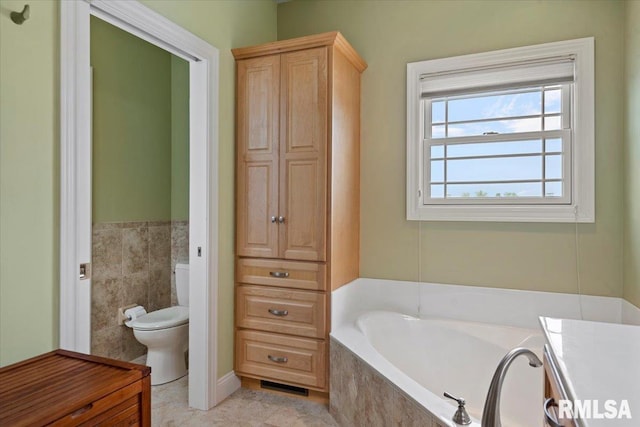 bathroom featuring toilet, tile patterned floors, and a garden tub