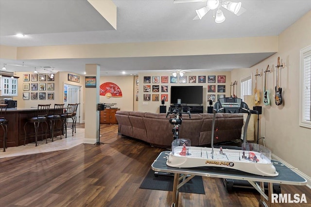 living room with a ceiling fan, baseboards, dark wood finished floors, and a dry bar