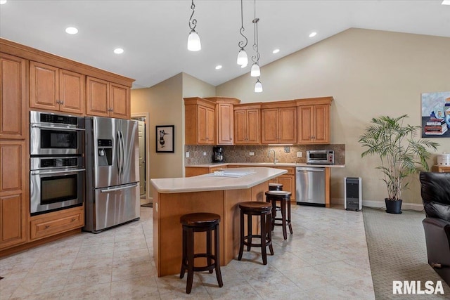 kitchen with a breakfast bar area, a center island, stainless steel appliances, backsplash, and light countertops